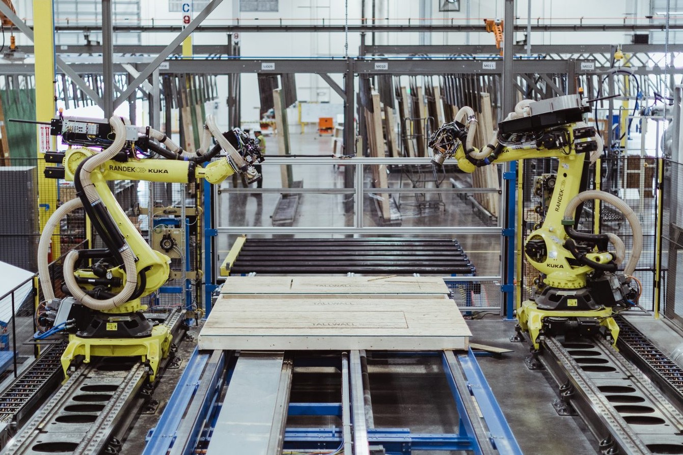 Robotic assembly line fabricating prefabricated wall panels