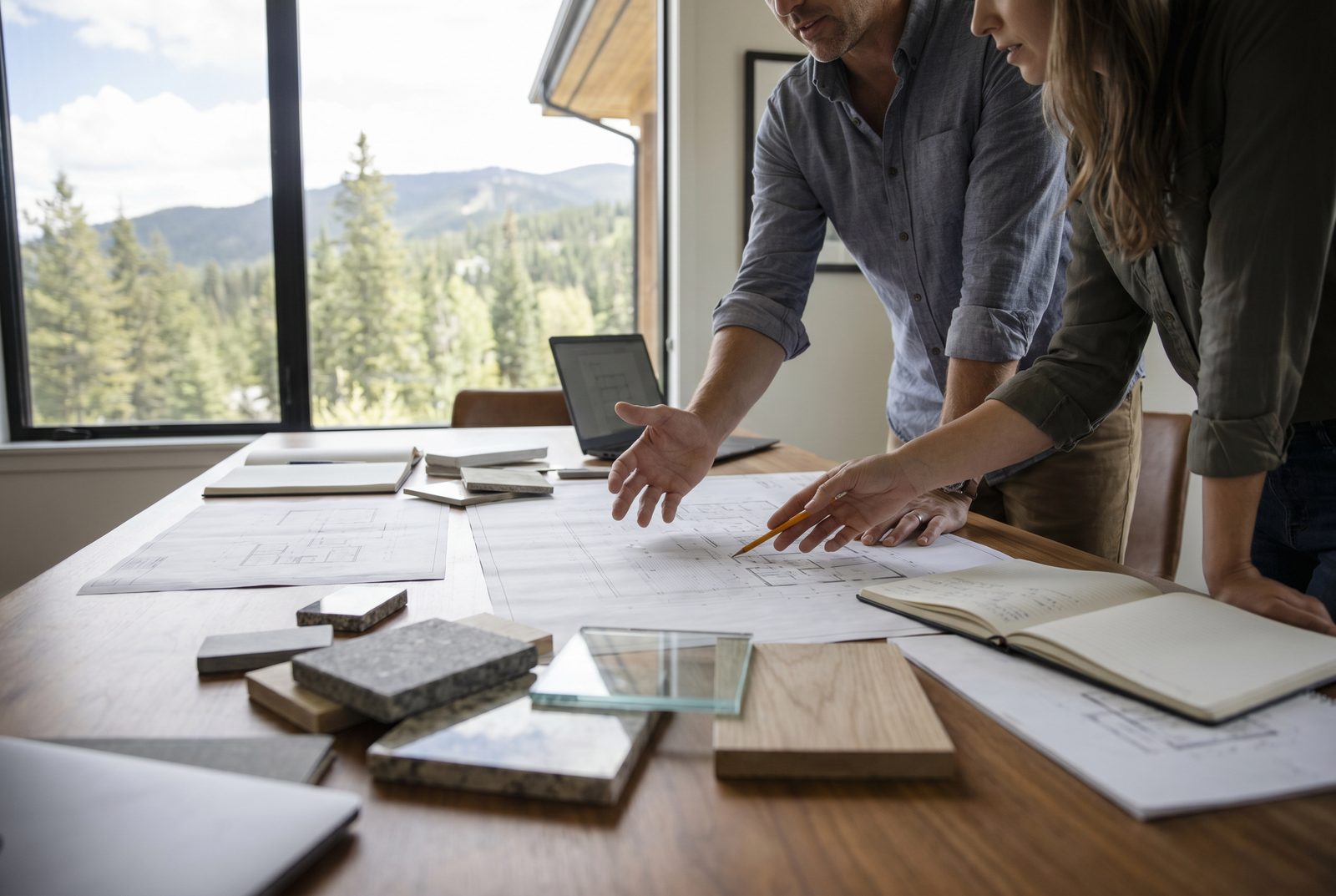 An architect and client working through floor plans together, material samples across the table